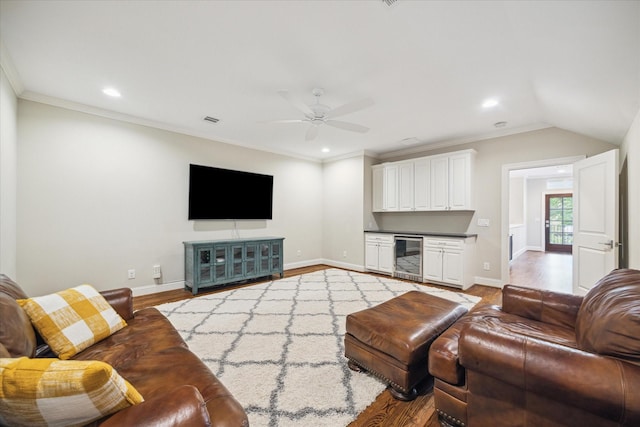 living room with crown molding, ceiling fan, beverage cooler, and wood-type flooring