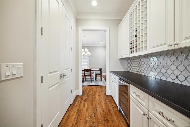 kitchen featuring decorative backsplash, dark wood-type flooring, white cabinetry, and crown molding