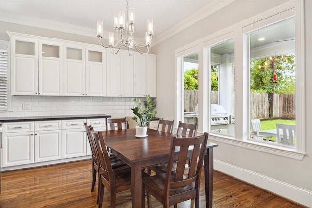 dining space featuring a notable chandelier, dark hardwood / wood-style flooring, and ornamental molding