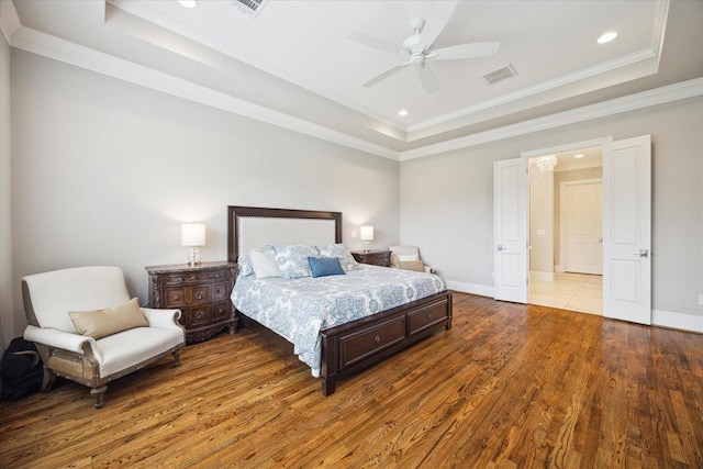 bedroom with ornamental molding, a tray ceiling, ceiling fan, and hardwood / wood-style flooring