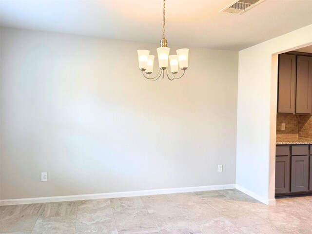 unfurnished dining area featuring baseboards, visible vents, and a chandelier