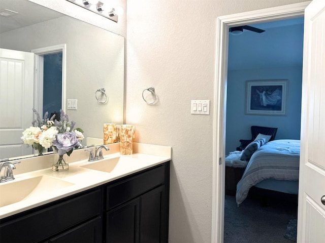 ensuite bathroom with a textured wall, double vanity, a sink, and ensuite bathroom