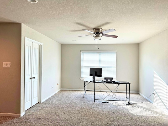 unfurnished office featuring ceiling fan, baseboards, a textured ceiling, and light colored carpet