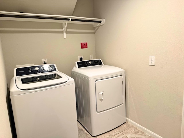 washroom featuring laundry area, baseboards, and separate washer and dryer