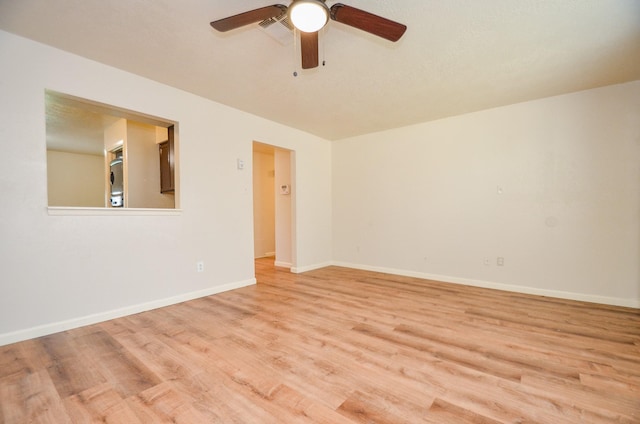 empty room with ceiling fan and light hardwood / wood-style flooring