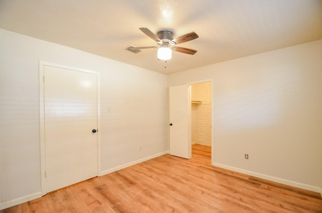 unfurnished bedroom with ceiling fan, a closet, a walk in closet, and light hardwood / wood-style flooring