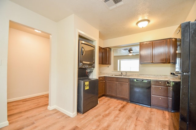 kitchen featuring black appliances, sink, ceiling fan, light wood-type flooring, and stacked washer / dryer