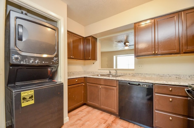 kitchen featuring ceiling fan, dishwasher, sink, stacked washer and clothes dryer, and light wood-type flooring