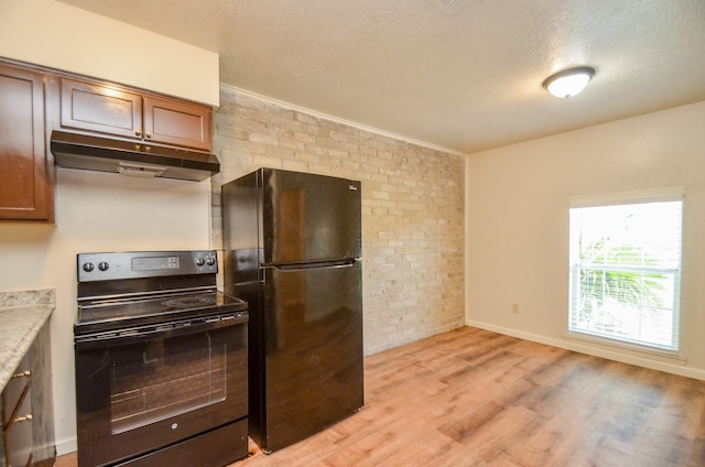 kitchen featuring black appliances, a textured ceiling, brick wall, and light hardwood / wood-style flooring