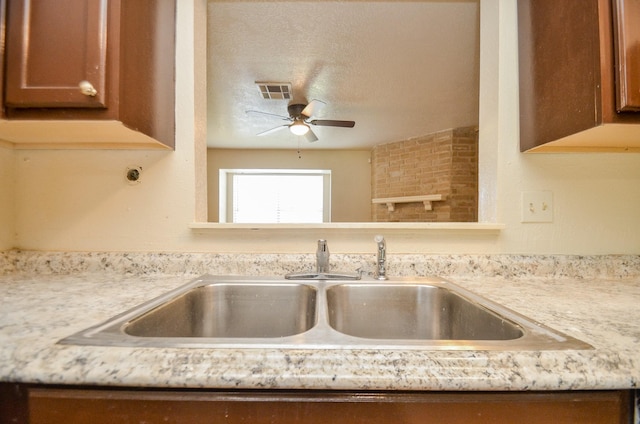 kitchen featuring light stone counters, sink, ceiling fan, and a textured ceiling