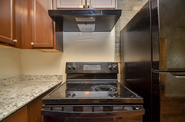 kitchen featuring light stone countertops, extractor fan, and black appliances