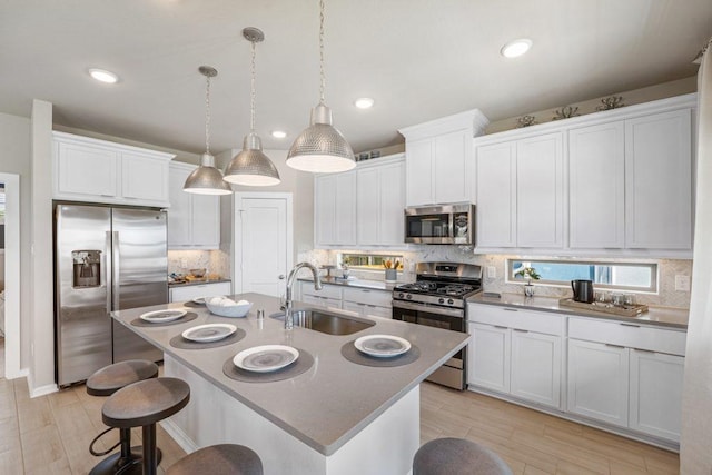 kitchen with backsplash, an island with sink, pendant lighting, and appliances with stainless steel finishes