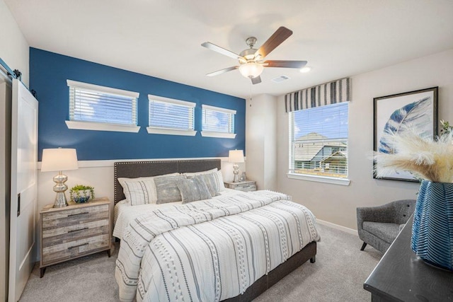 bedroom with a barn door, light colored carpet, and ceiling fan