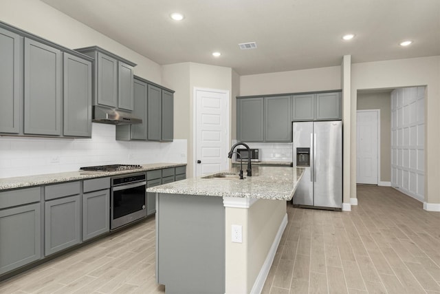 kitchen featuring gray cabinets, sink, an island with sink, and stainless steel appliances