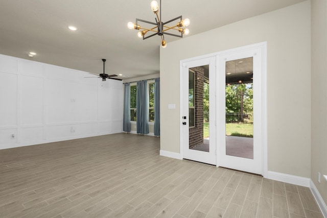 spare room featuring ceiling fan with notable chandelier