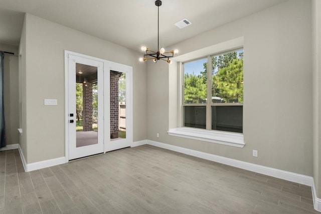 unfurnished dining area featuring light hardwood / wood-style flooring and a notable chandelier