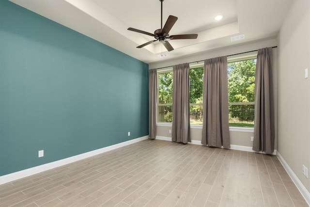 unfurnished room featuring light wood-type flooring, a raised ceiling, and ceiling fan