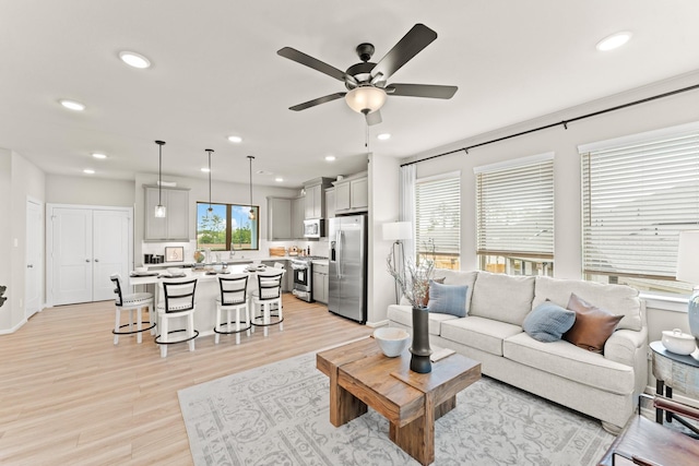 living room featuring ceiling fan, plenty of natural light, and light wood-type flooring