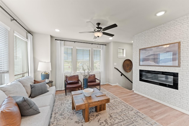 living room featuring a fireplace, light wood-type flooring, a healthy amount of sunlight, and brick wall