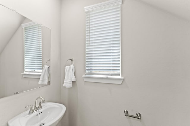 bathroom featuring lofted ceiling, a healthy amount of sunlight, and sink