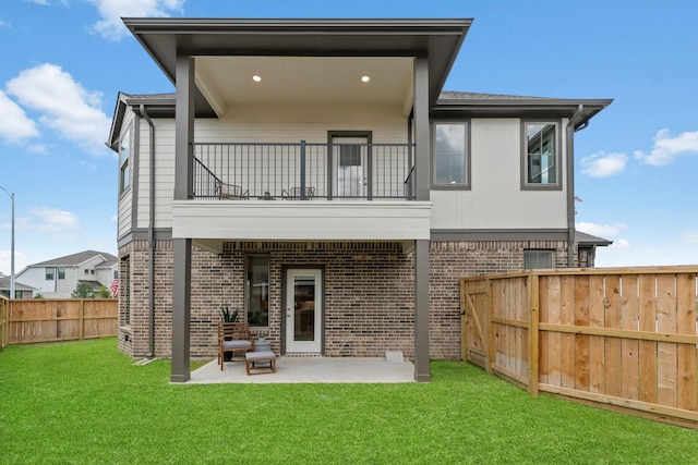 rear view of property with a lawn, a patio area, and a balcony