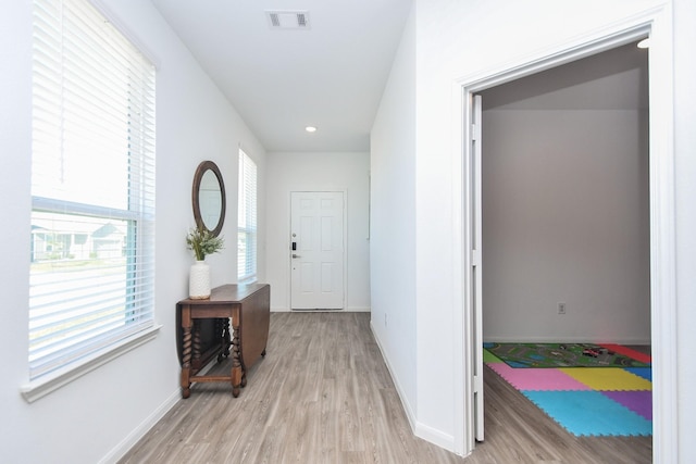 corridor featuring a healthy amount of sunlight and light hardwood / wood-style floors