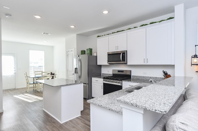 kitchen featuring white cabinets, sink, appliances with stainless steel finishes, a kitchen island, and a breakfast bar area