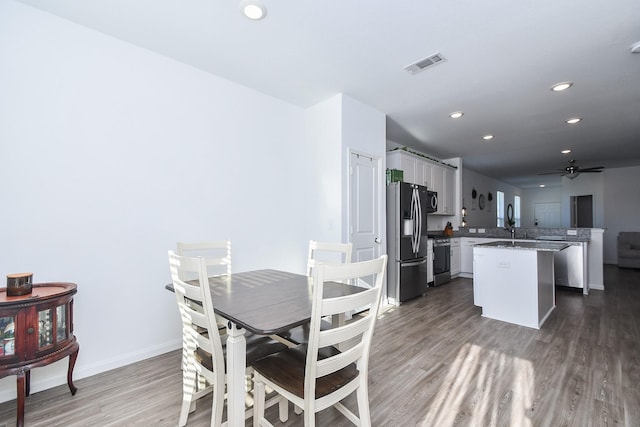 dining area with ceiling fan, wood-type flooring, and sink