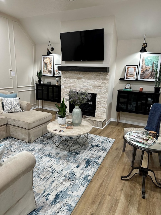 living room with a fireplace, vaulted ceiling, and light hardwood / wood-style flooring