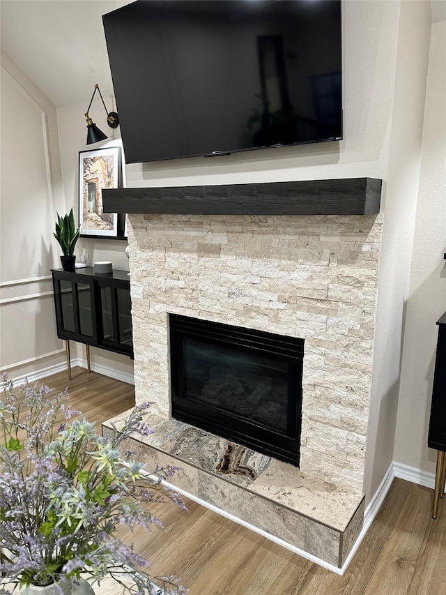 room details with hardwood / wood-style floors and a stone fireplace