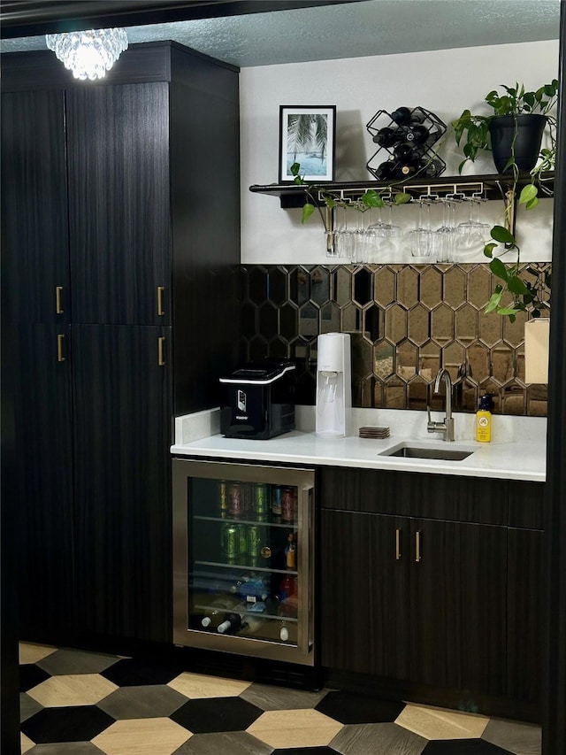 bar featuring tasteful backsplash, a chandelier, sink, and beverage cooler