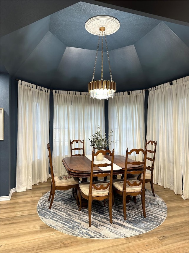 dining space featuring an inviting chandelier, wood-type flooring, and vaulted ceiling