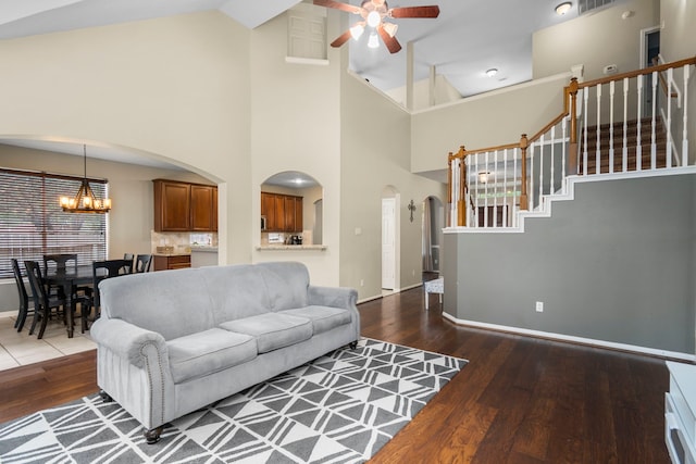 living room featuring hardwood / wood-style floors, ceiling fan with notable chandelier, and high vaulted ceiling