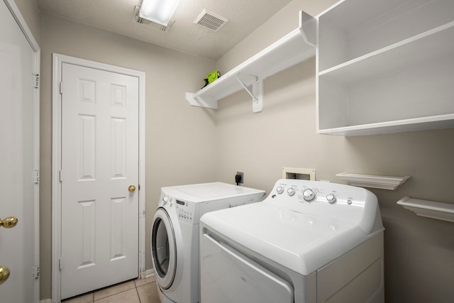 laundry area with separate washer and dryer and light tile patterned floors