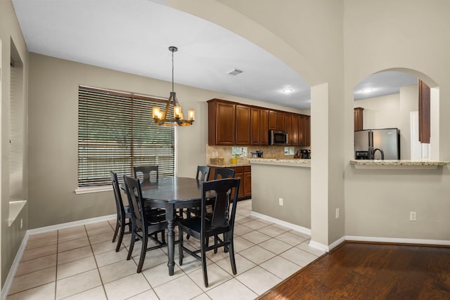 tiled dining space featuring a notable chandelier