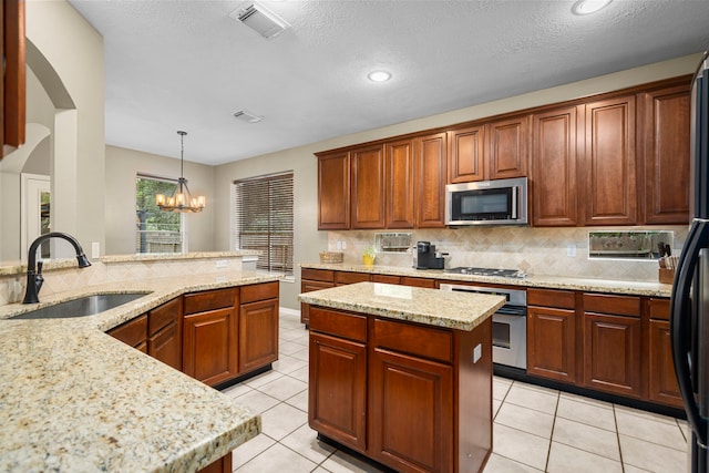 kitchen featuring appliances with stainless steel finishes, sink, decorative light fixtures, a chandelier, and a center island