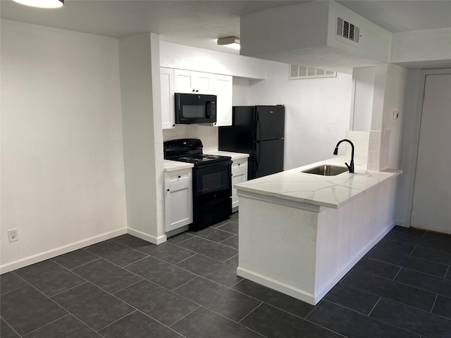 kitchen with black appliances, white cabinets, sink, light stone countertops, and kitchen peninsula