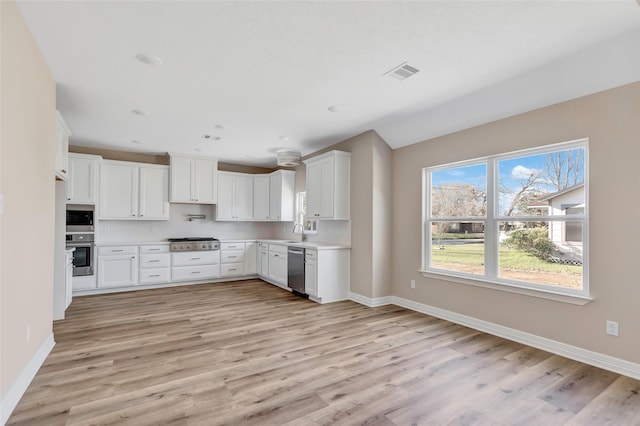 kitchen with white cabinets, appliances with stainless steel finishes, light wood-type flooring, and sink