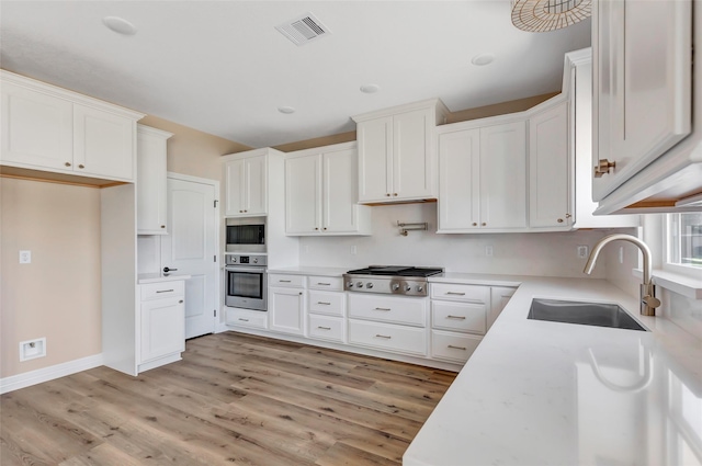 kitchen featuring white cabinetry, sink, stainless steel appliances, and light hardwood / wood-style flooring