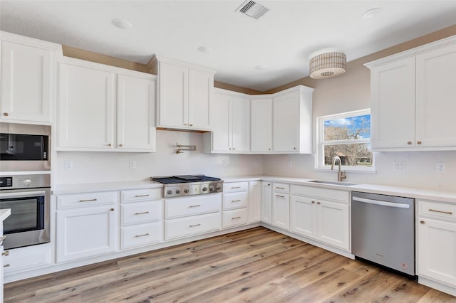 kitchen featuring white cabinets, sink, stainless steel appliances, and light hardwood / wood-style flooring