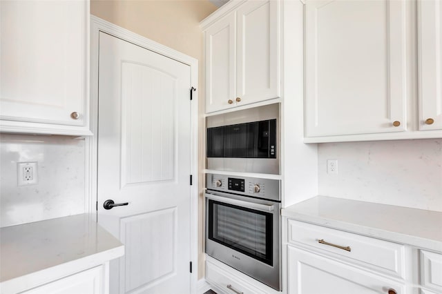 kitchen featuring white cabinets, built in microwave, and stainless steel oven