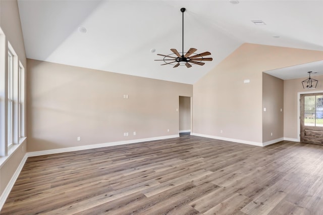 unfurnished living room featuring vaulted ceiling, light hardwood / wood-style floors, and ceiling fan with notable chandelier