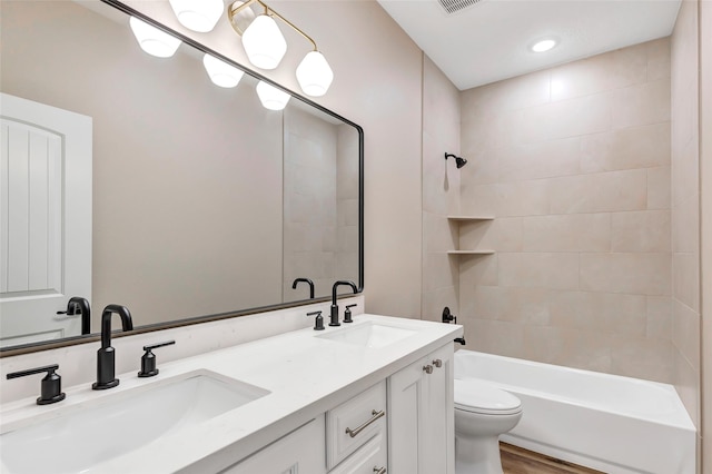 full bathroom featuring hardwood / wood-style floors, vanity, tiled shower / bath combo, and toilet