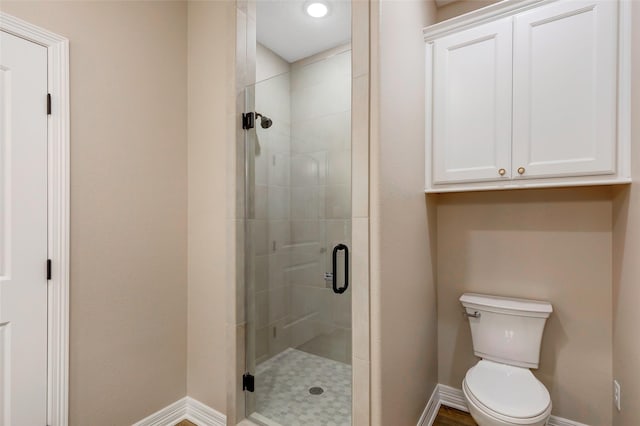 bathroom featuring toilet and a shower with shower door