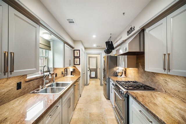 kitchen featuring appliances with stainless steel finishes, backsplash, light stone counters, and sink