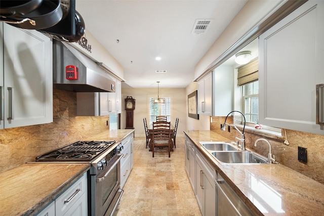 kitchen with light stone countertops, sink, stainless steel appliances, pendant lighting, and decorative backsplash