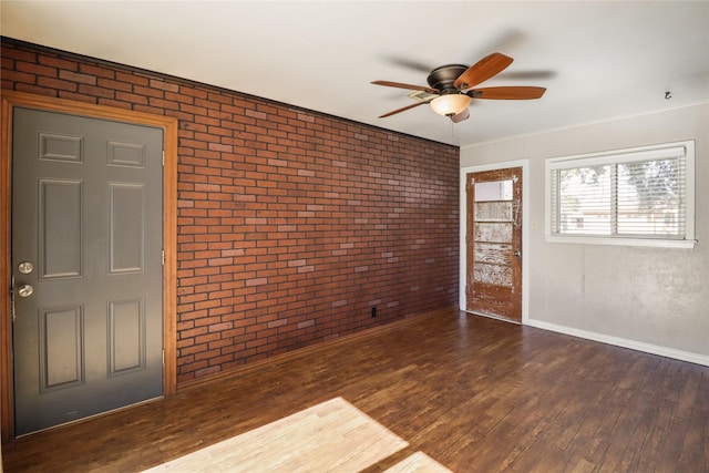 foyer entrance with ceiling fan, dark wood-type flooring, and brick wall