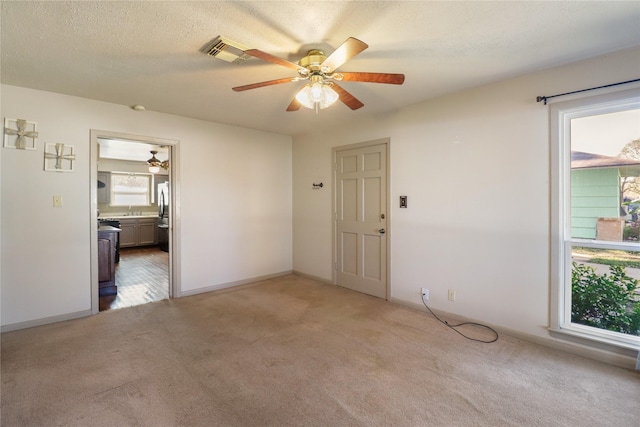 unfurnished room featuring ceiling fan, light colored carpet, and a wealth of natural light