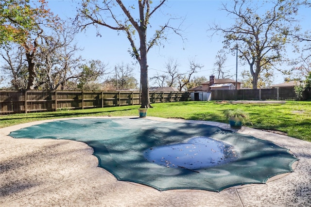 view of swimming pool with a lawn and a storage unit