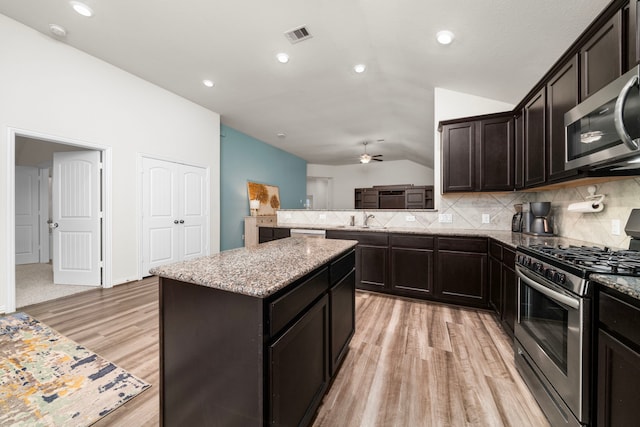 kitchen with ceiling fan, a center island, sink, stainless steel appliances, and lofted ceiling